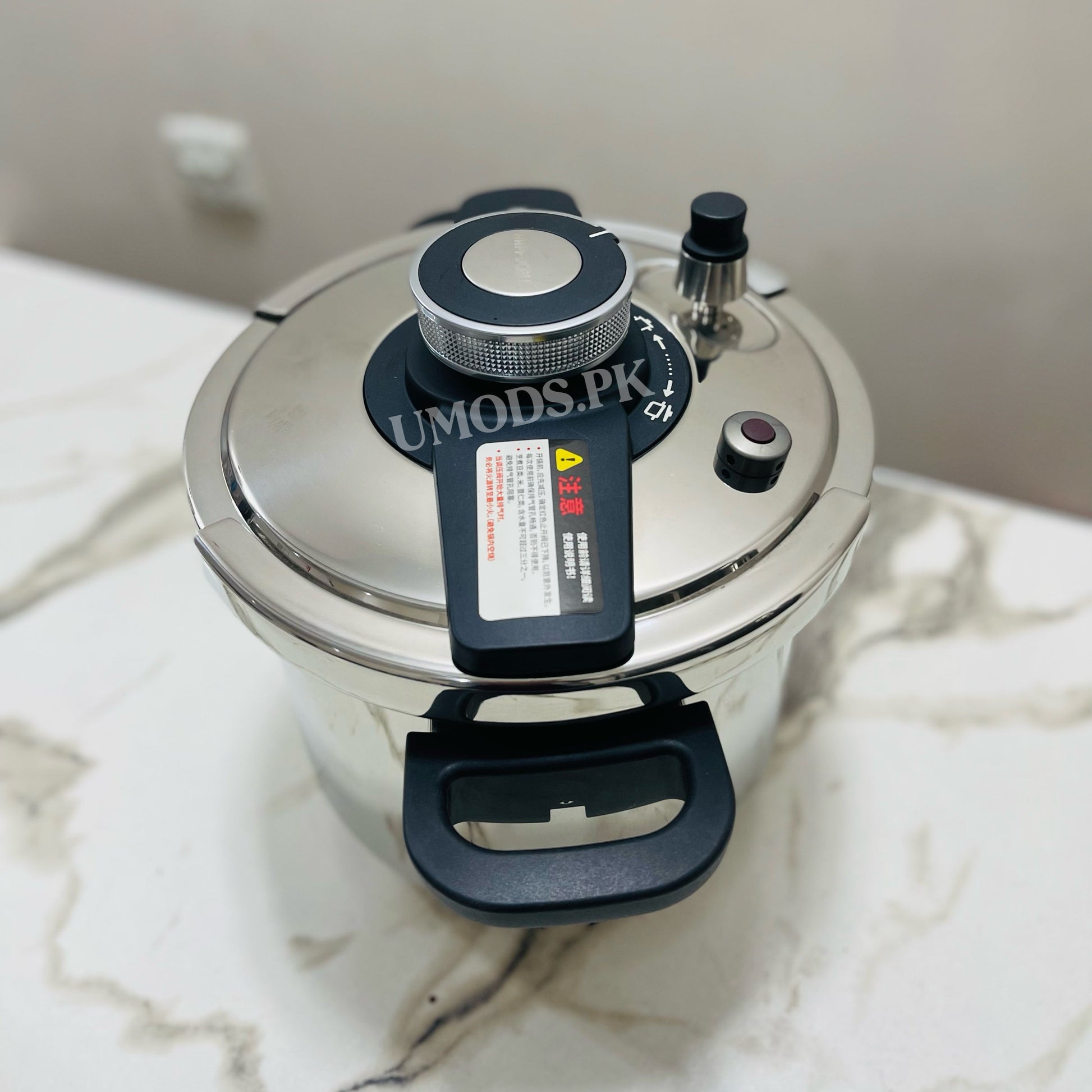 Pressure cooker with a visible brand label on a marble surface